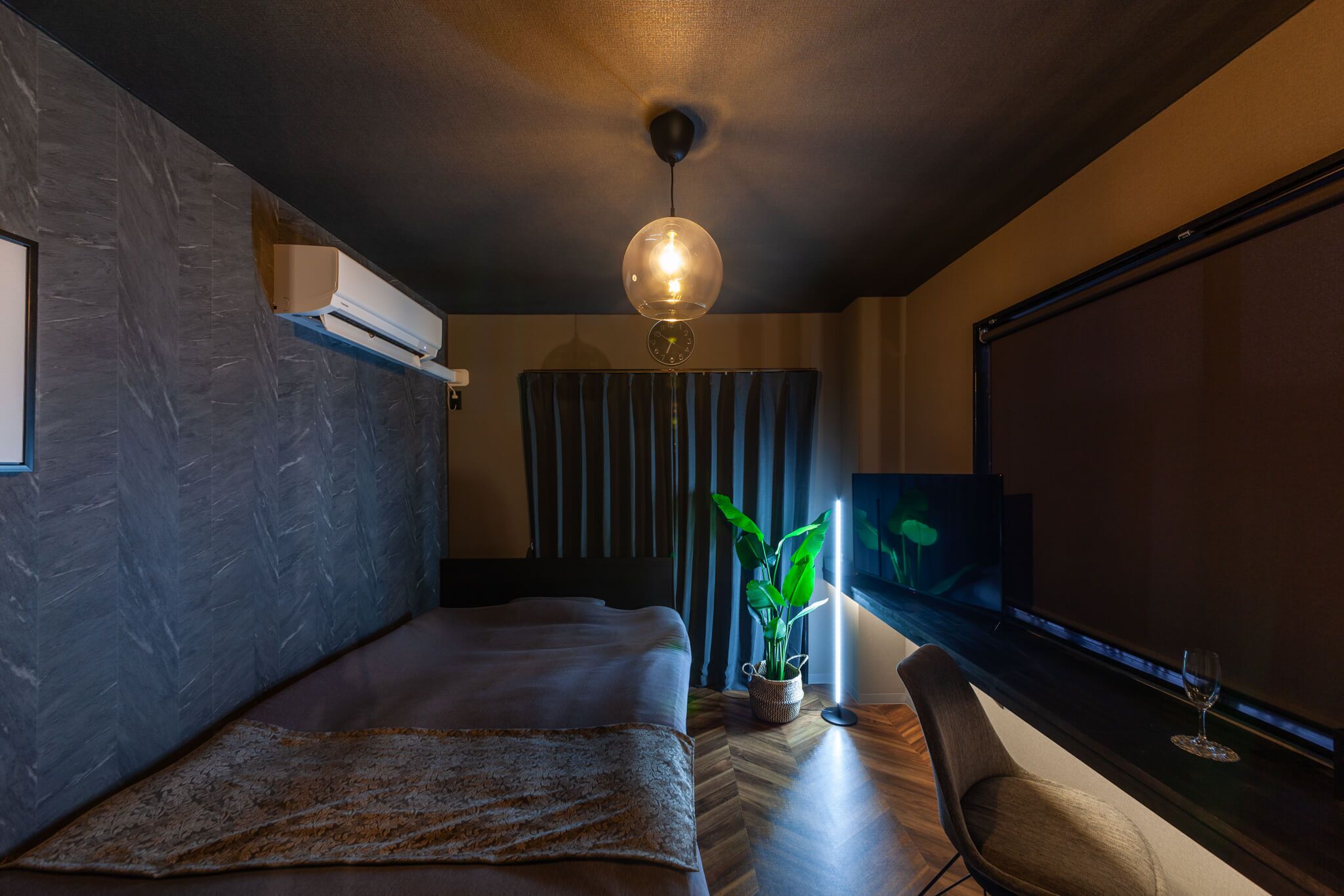 A modern bedroom with a bed, a potted plant, a TV, and a window.