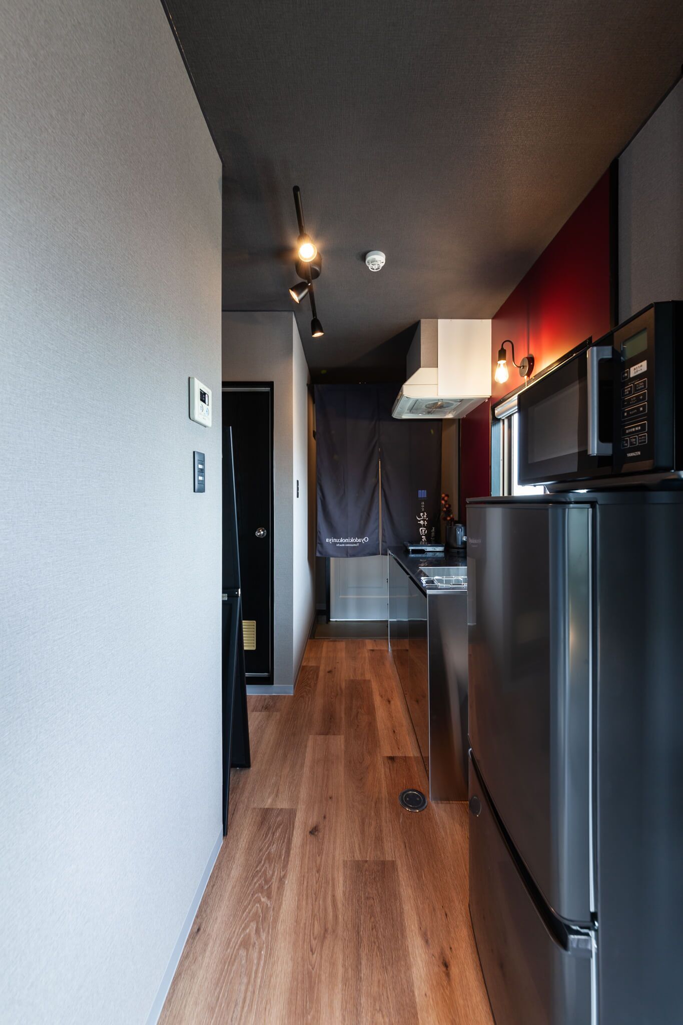A modern kitchen with a stainless steel refrigerator, a microwave, and a wooden floor.