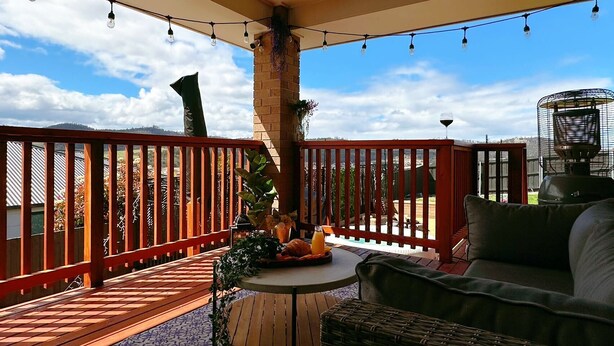 A covered outdoor area with a round table, a sofa, and a heater.