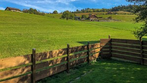 Un campo cubierto de césped con una valla de madera y un edificio al fondo.