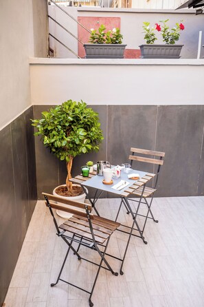 A small outdoor patio with a table and chairs, a potted tree, and a few potted plants. - MEDUSA CILEA GUEST HOUSE (Naples)