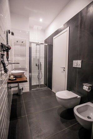 A modern bathroom with a white sink, a toilet, a bidet, and a glass-enclosed shower. - MEDUSA CILEA GUEST HOUSE (Naples)