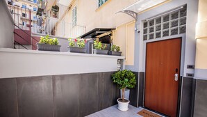 A modern building entrance with a wooden door, a welcome mat, and potted plants on a balcony. - MEDUSA CILEA GUEST HOUSE (Naples)