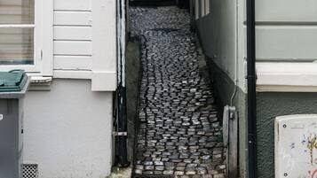 A narrow cobblestone alleyway between buildings with a 'Stay' sign on the left.