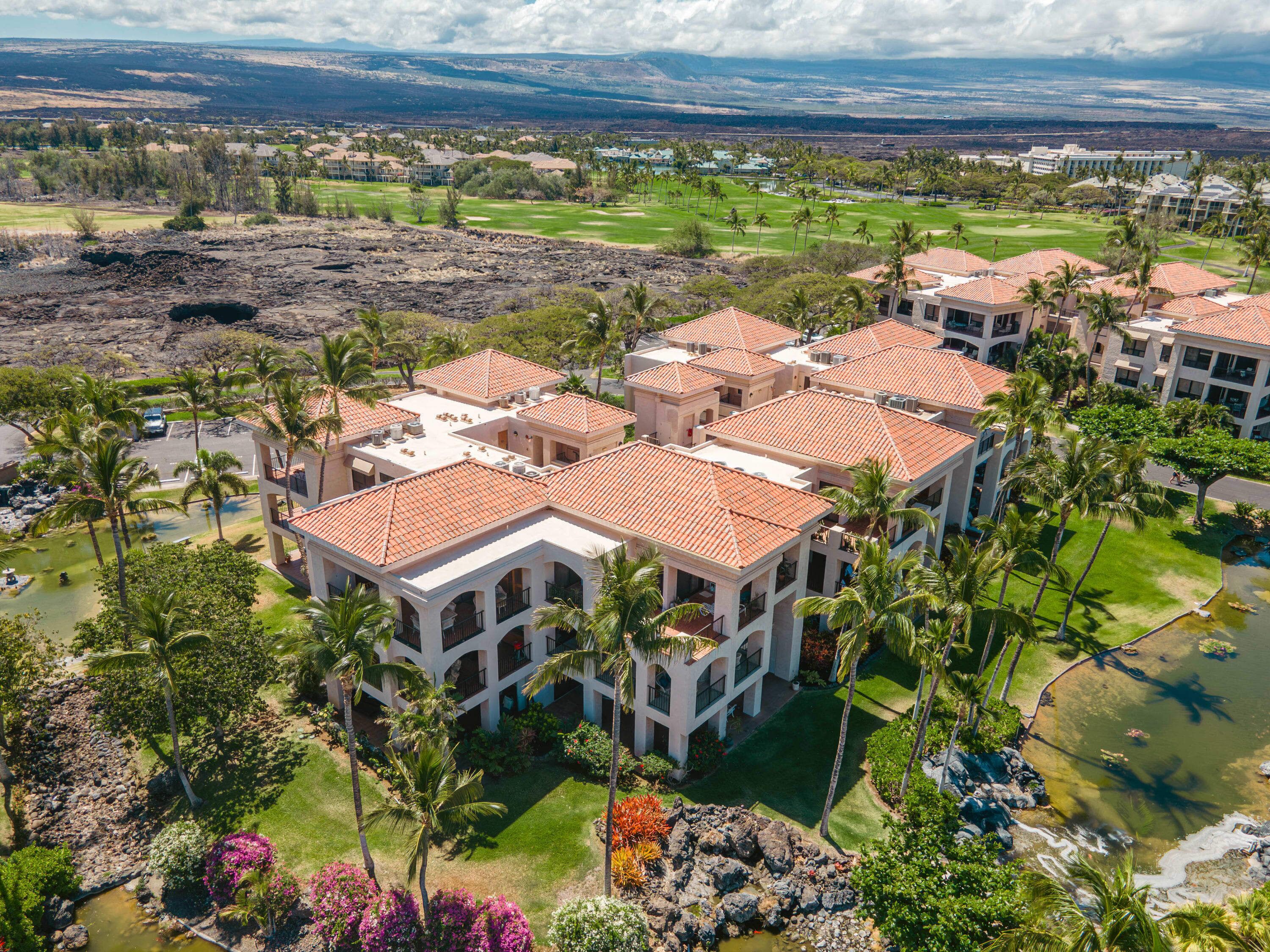 Un resort con diversi edifici, un campo da golf e vista su montagne lontane.