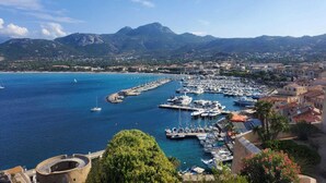 A coastal marina with boats docked, surrounded by residential buildings and mountains in the background. - New Villa Sea and Mountain View - Calenzana, near Calvi  (Calenzana)