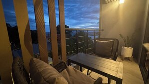 Un balcón con mobiliario de mimbre, una mesa y una planta en maceta.
