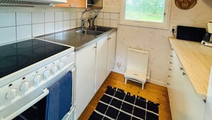 A compact kitchen with a stove, sink, and a window. - 6 Person Holiday Home in Henan (Henån)