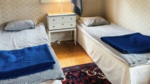 A small bedroom with two beds, a nightstand, a lamp, and a window with a view of trees. - 6 Person Holiday Home in Henan (Henån)