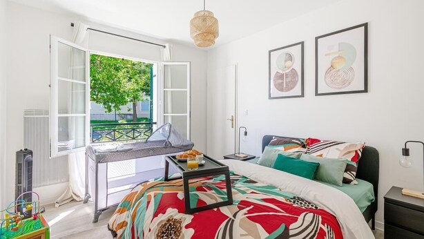 Een slaapkamer met een bed, een bureau en een raam met uitzicht op groen.