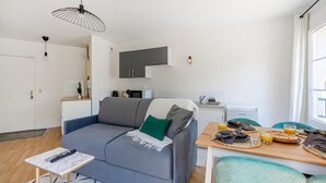Een moderne woonkamer met een grijze bank, een klein houten tafeltje en een ontbijtje op een dienblad.