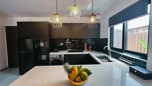 A modern kitchen with a central island, black appliances, and pendant lighting. - Hibiscus Suites And Residences  (Nadi)