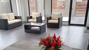 A modern living room with a glass coffee table, two sofas, and a decorative vase of flowers. - Hibiscus Suites And Residences  (Nadi)