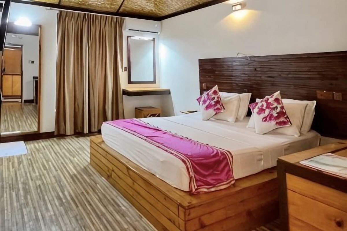 Una habitación de hotel con una cama de madera, una mesita de noche, un espejo y una ventana con cortinas.