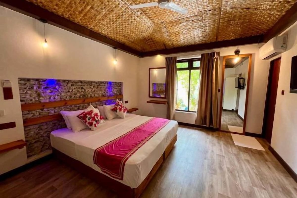 Un dormitorio con pared de piedra, estructura de cama de madera y ventilador de techo.