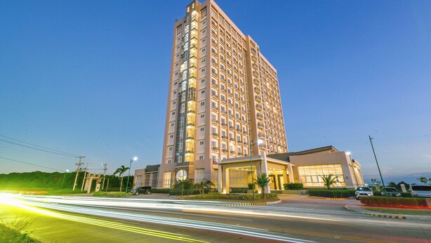 A multi-story hotel with a modern design, featuring a prominent entrance and a well-lit facade. - Sotogrande Hotel and Convention Center Batangas (Bauan)