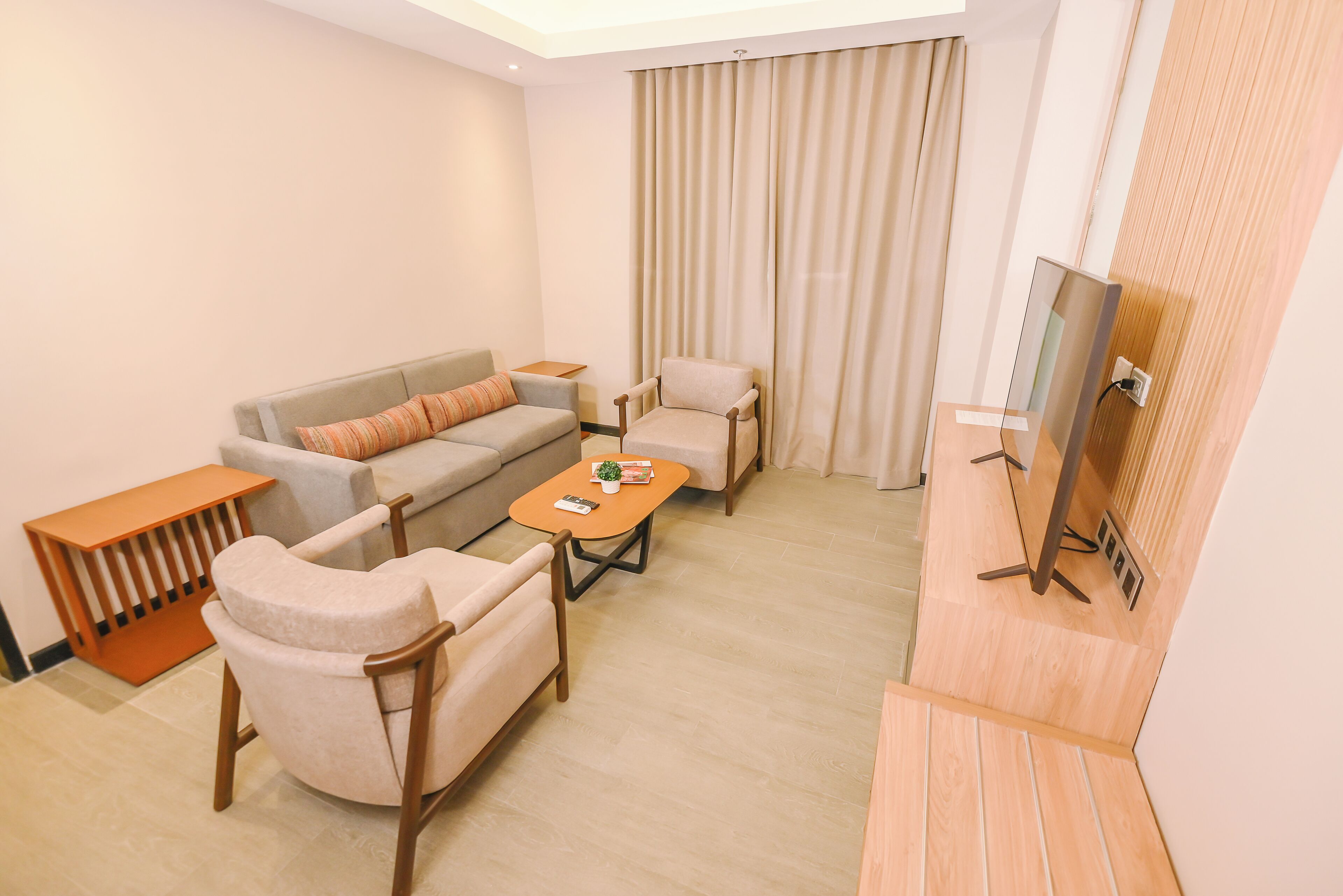 A modern living room with a sofa, armchairs, a coffee table, and a television.