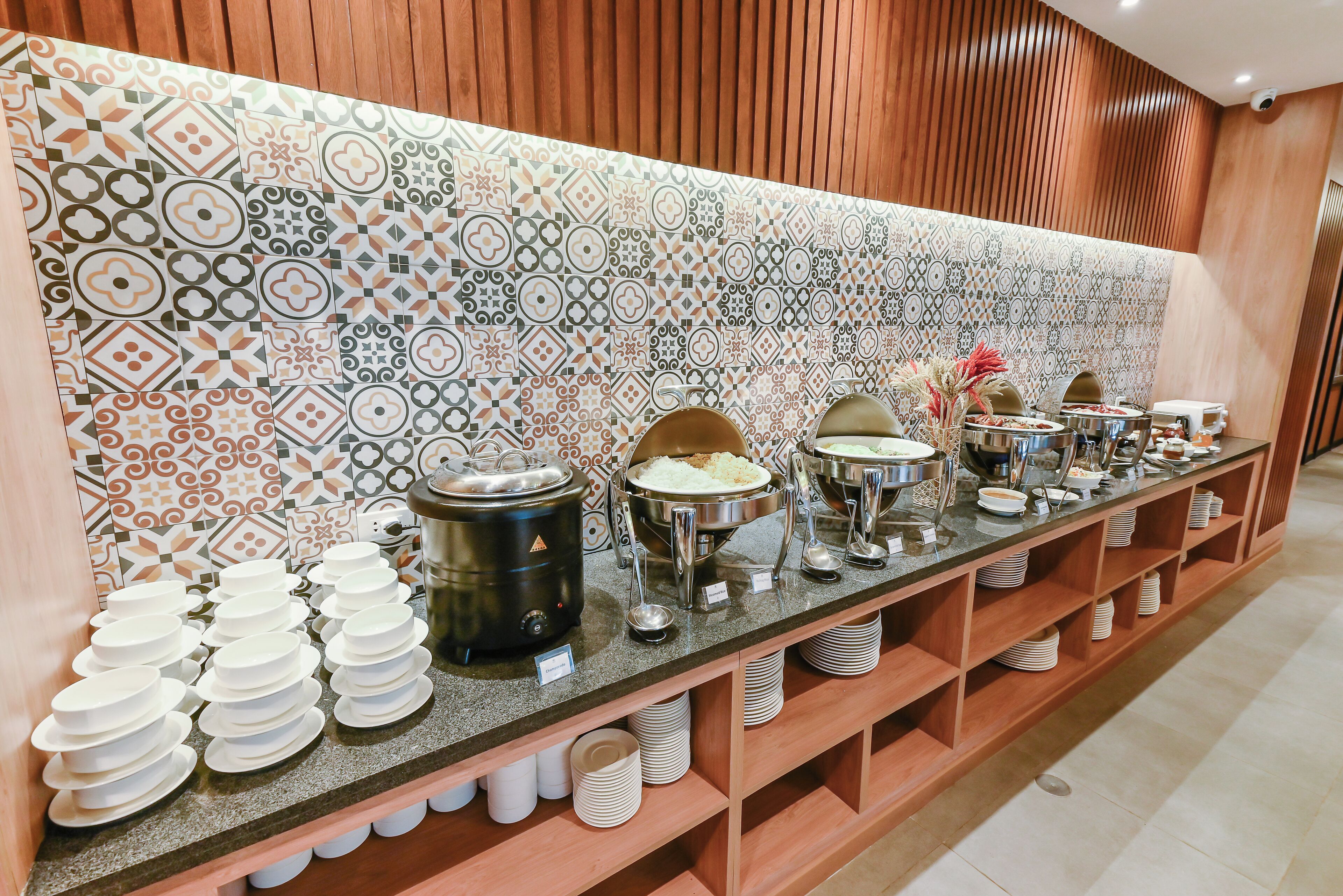 En buffet med forskellige madbeholdere og stablede tallerkener.