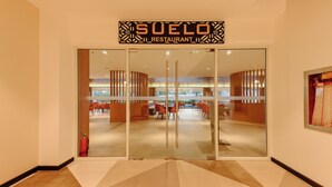 The entrance to Suele Restaurant with a modern interior visible through the glass doors. - Sotogrande Hotel and Convention Center Batangas (Bauan)