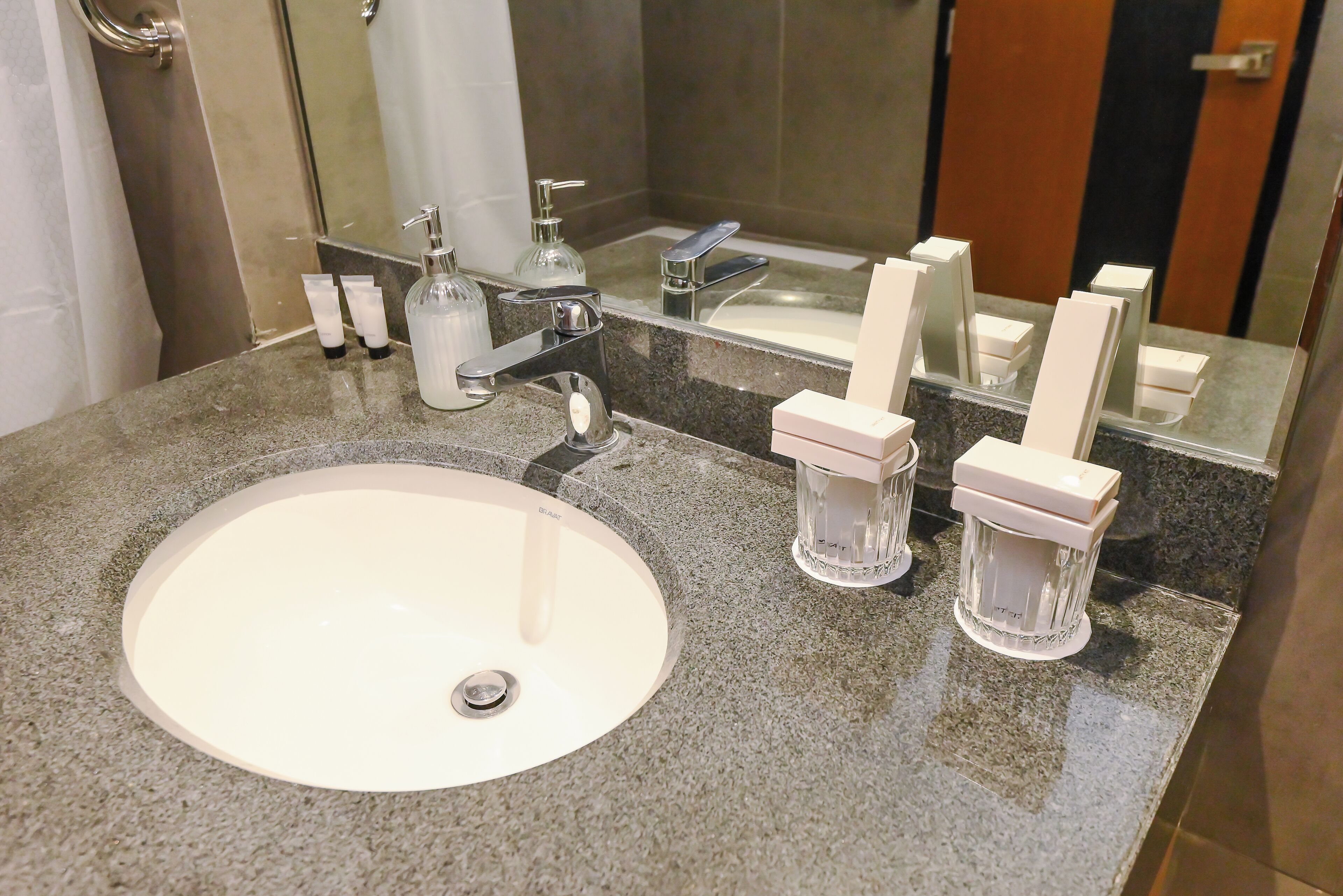 Un bagno con un lavandino bianco, uno specchio e articoli da toilette sul ripiano.