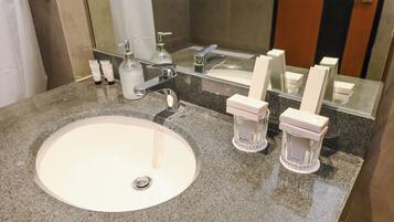 Un bagno con un lavandino bianco, uno specchio e articoli da toilette sul ripiano.