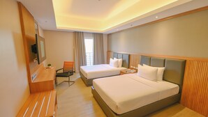 A hotel room with two beds, a desk, a chair, a TV, and a window with curtains. - Sotogrande Hotel and Convention Center Batangas (Bauan)
