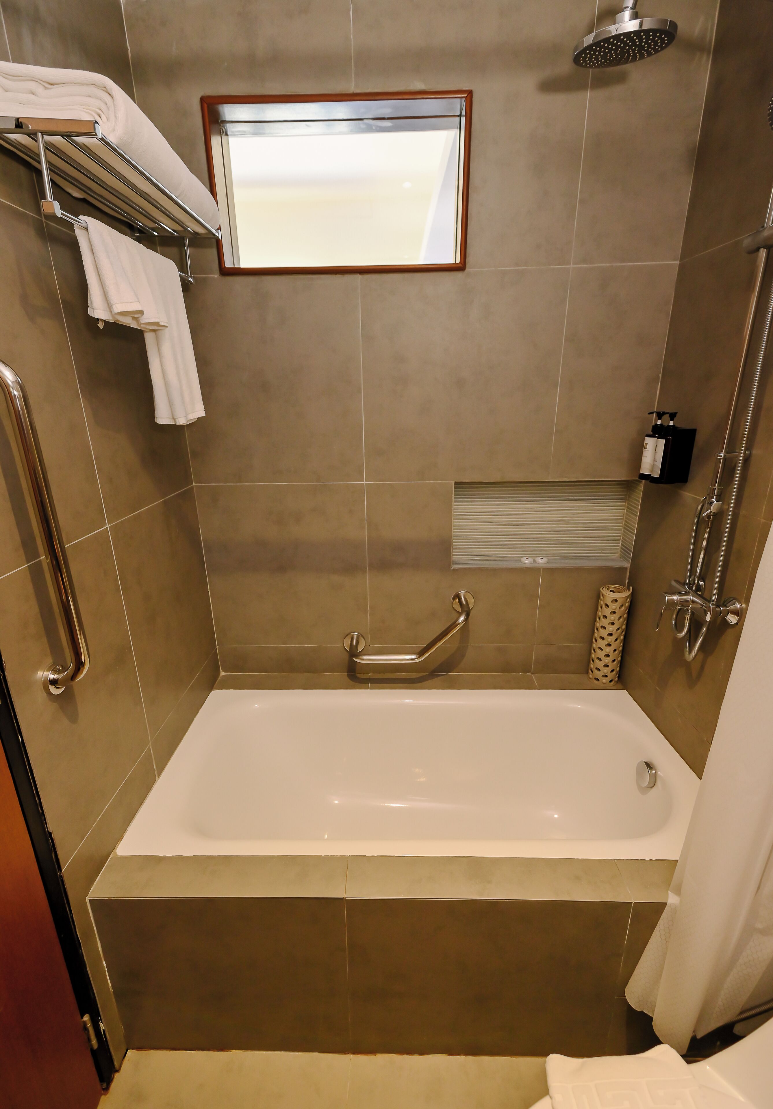 A bathroom with a bathtub, a shower, and a handrail.
