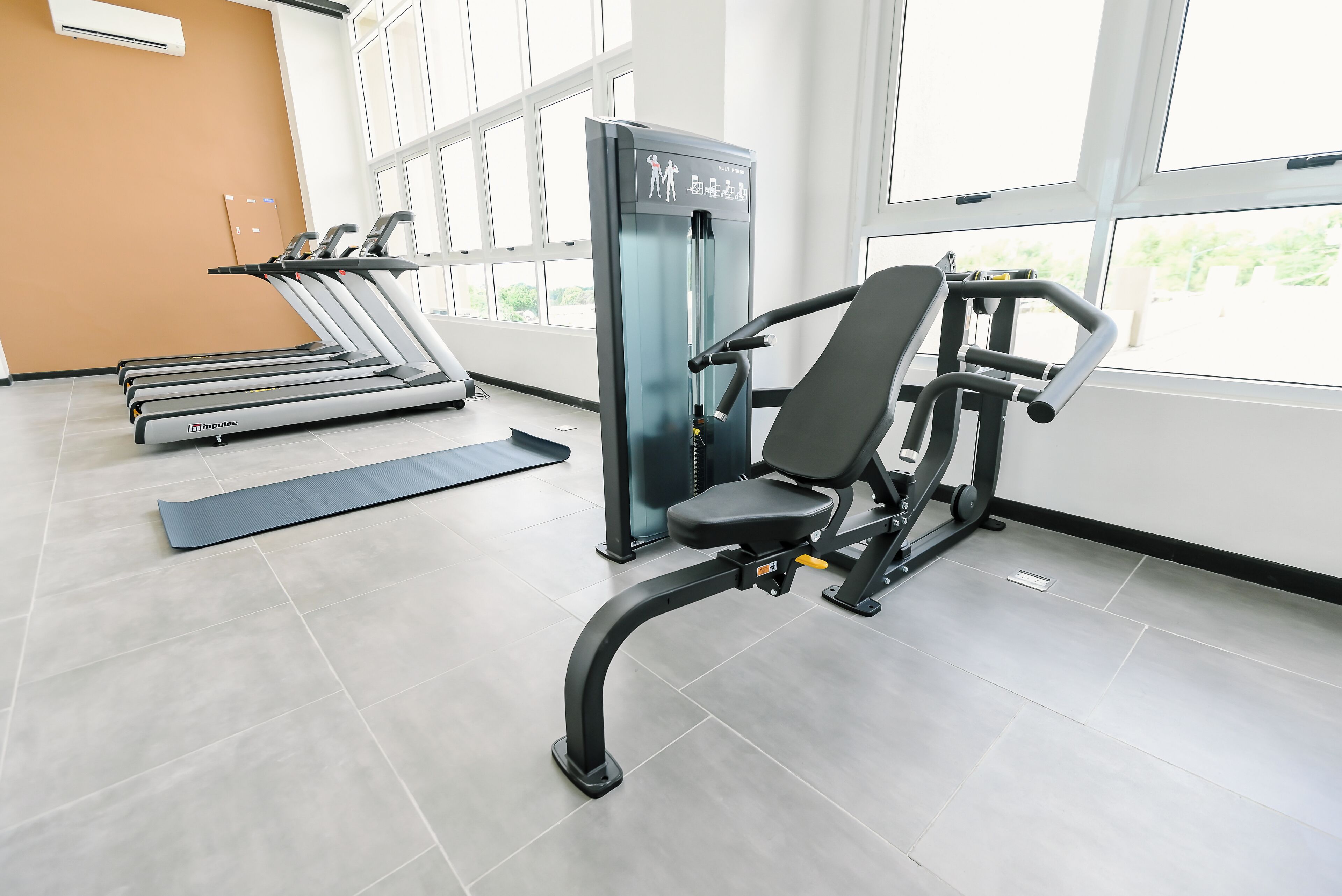 A gym with treadmills, a weight machine, and a yoga mat.
