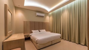 Habitació d'hotel moderna amb un llit gran, una taula de nit i aire condicionat fixat a la paret.
