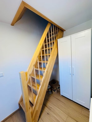 A wooden staircase with a wooden handrail and a white door at the bottom. - Antonia Vacation Home (Varel)