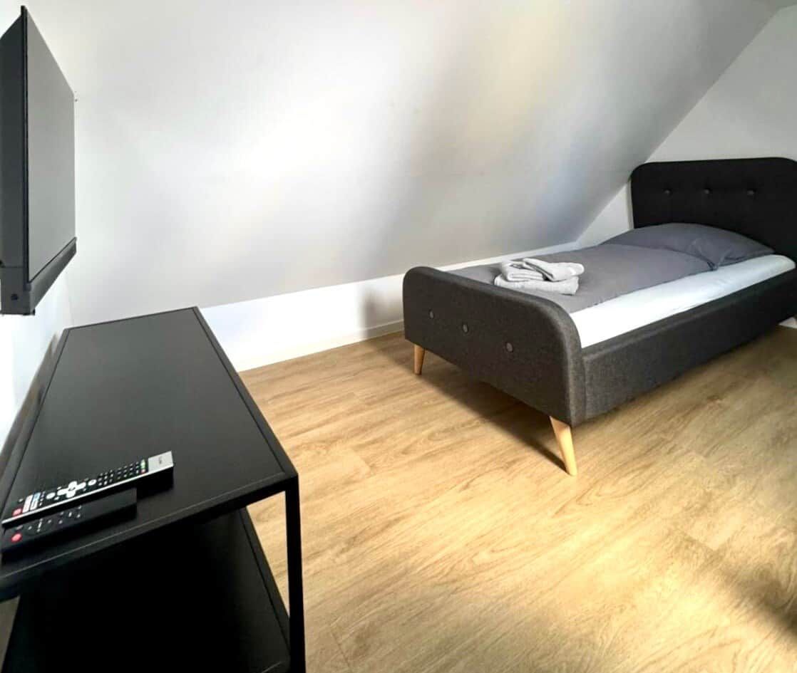 A small room with a bed, a TV, and a table.
