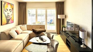 Ein modernes Wohnzimmer mit einer Couch, einem Couchtisch, einem Fernseher und einer Lampe.