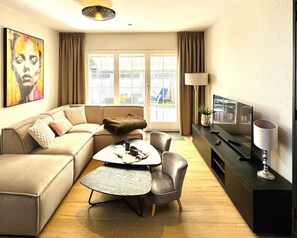 A modern living room with a sofa, a coffee table, a TV, and a lamp. - Antonia Vacation Home (Varel)