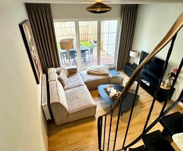 A living room with a sofa, a coffee table, and a TV. There is a staircase leading to another level. - Antonia Vacation Home (Varel)