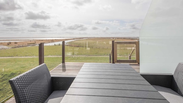 Une terrasse extérieure moderne offrant une vue sur une rivière et des champs.