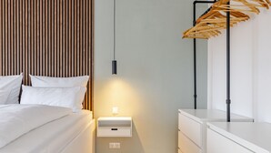 A modern bedroom with a bed, bedside table, and a wooden wall panel.