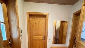 Un couloir avec des portes en bois, un sol carrelé et un petit banc en bois.