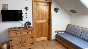 Une pièce chaleureuse avec un meuble en bois, un téléviseur, un canapé bleu et une porte en bois.