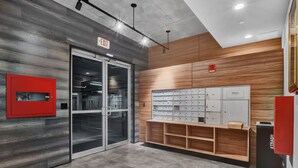 A modern office interior with a glass door entrance, a red trash bin, and a white storage unit with multiple drawers.
