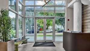 A modern reception area with a glass door entrance, a reception desk, and a bench.