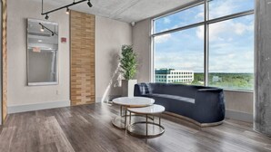 A modern office space with a large window, a round table, a sofa, and a plant.