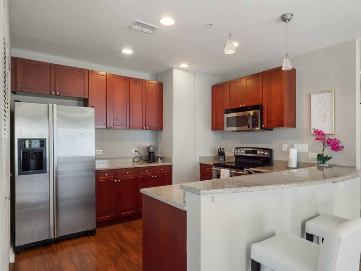 Una cocina moderna con electrodomésticos de acero inoxidable, armarios de madera y una isla central con asientos.