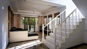 A spacious living room with a white staircase, large windows, and a ceiling fan. - Mountain View Villa Kamala (Kamala Subdistrict, Kathu District)