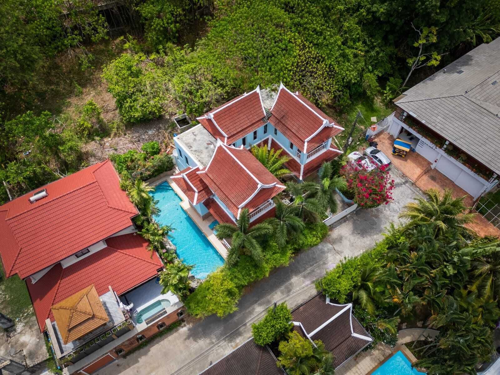A large house with a swimming pool, surrounded by lush greenery.