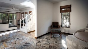 A spacious living area with a marble floor, a wicker chair, and a sofa. - Mountain View Villa Kamala (Kamala Subdistrict, Kathu District)
