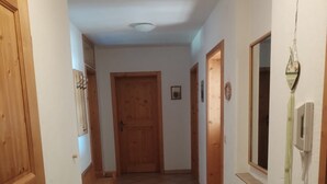 Un pasillo con suelo de baldosas, puertas de madera y un banco.