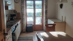 Una cocina compacta con comedor, un reloj y una ventana con cortinas.