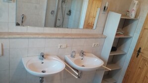Un baño con dos lavamanos, un espejo y una ducha.