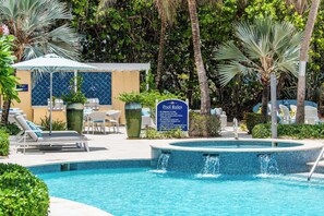 Un espace piscine avec des chaises longues, un panneau indiquant les règles d’utilisation de la piscine et un petit jacuzzi.