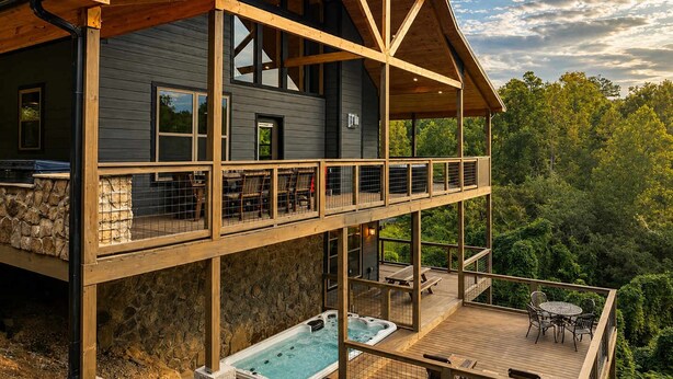 Una casa de dos pisos con balcón, jacuzzi y mobiliario exterior.